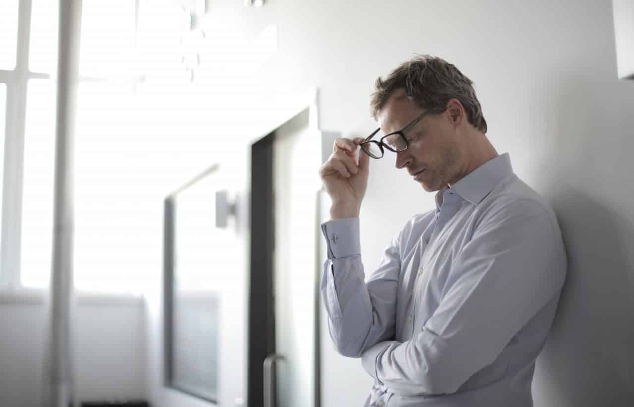 Stressed-looking man leaning against a wall.