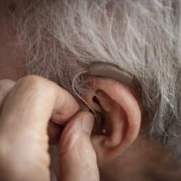Close up of man adjusting hearing aid