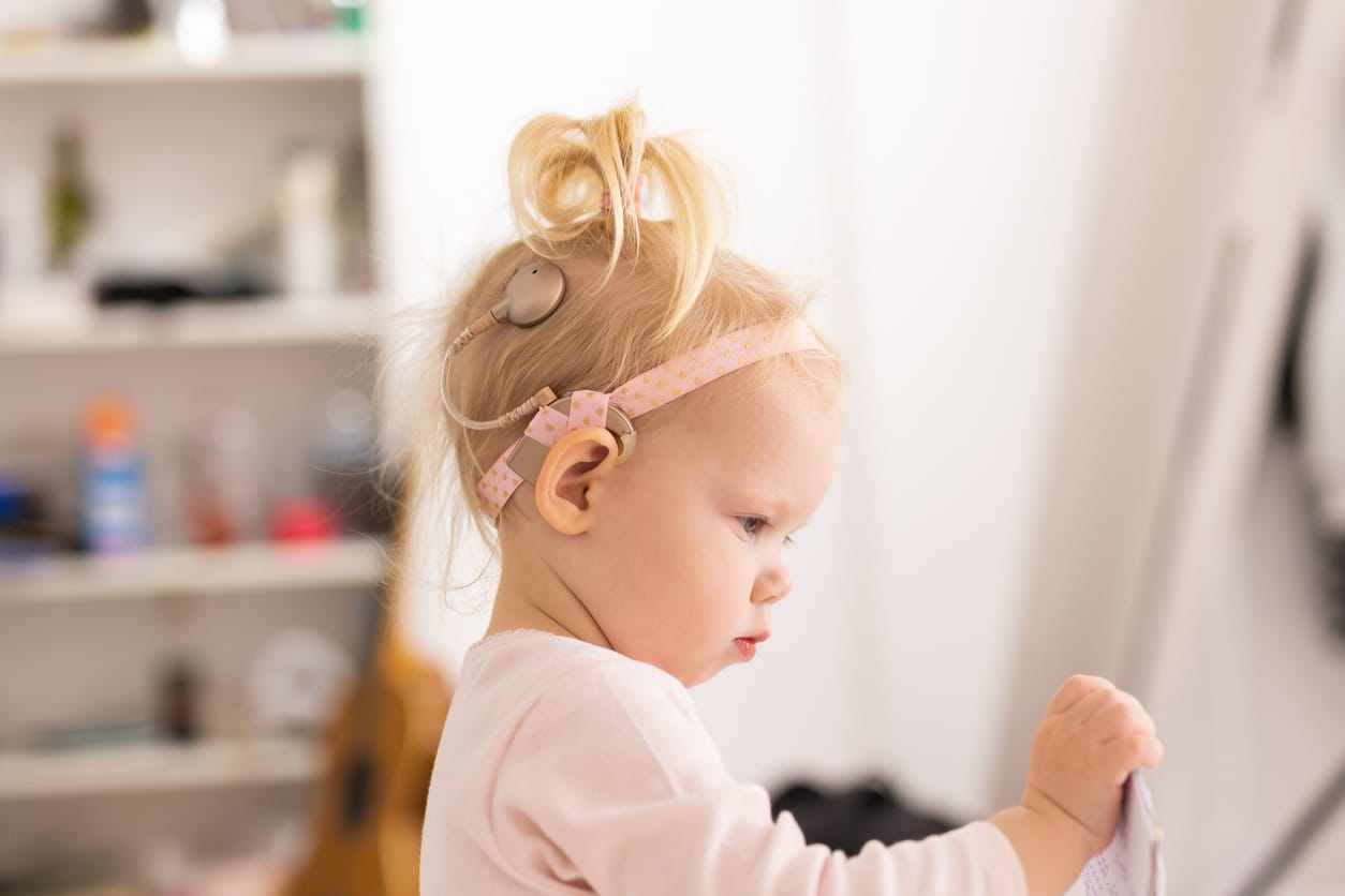 Young girl with hearing aids holding paper.