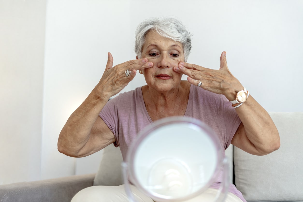 Senior woman putting on makeup.