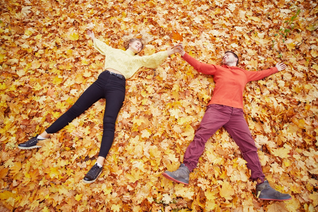 Young couple laying in the autumn leaves.